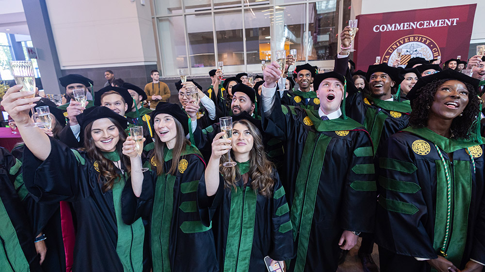 Stritch School of Medicine Class of 2025 graduates celebrating at commencement with a champagne toast.