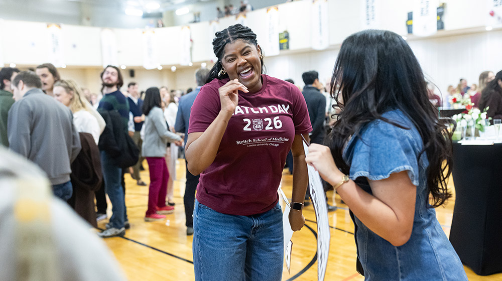 A student wearing a maroon Match Day 2026 t-shirt jumps for joy