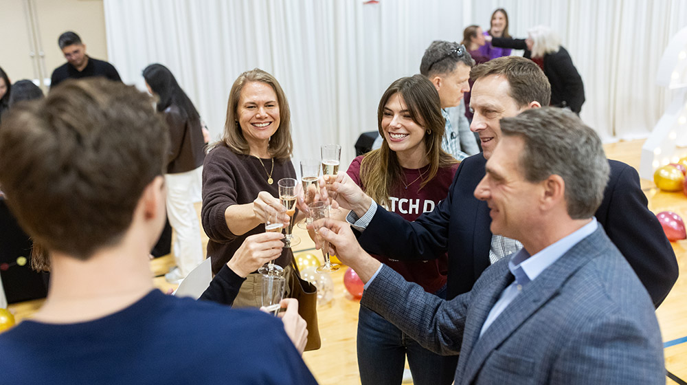 A student wearing a maroon Match Day t-shirt and her family members having a champagne toast